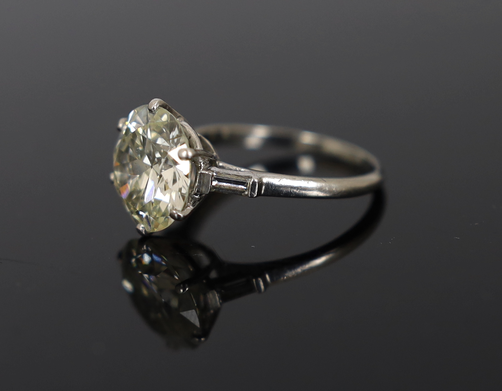 A platinum and single stone diamond set ring, with baguette cut diamond set shoulders